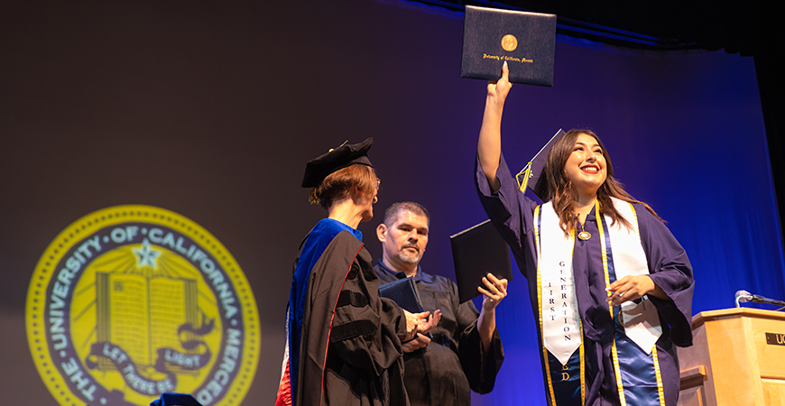 A graduating student holds up a diploma cover.