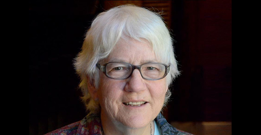 Close-up photo of caucasian woman in glasses with short white hair.