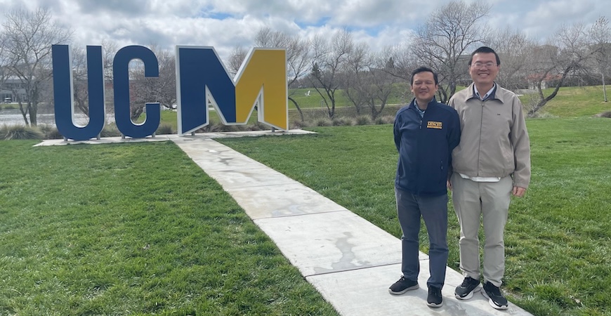 Photo depicts the blue and gold UCM art installation and professors Chih-Chun Chien, left, and Xiaoyi Lu