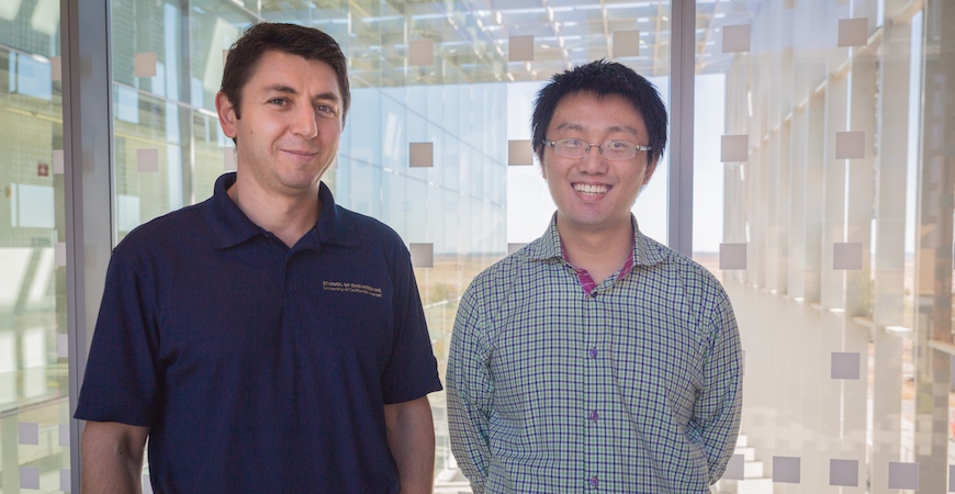 Professor Florin Rusu and graduate student Weijie Zhao pose in front of patterned panes of glass.