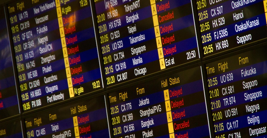 Stock image depicts an electronic flight board with multiple delays at an unnamed airport.