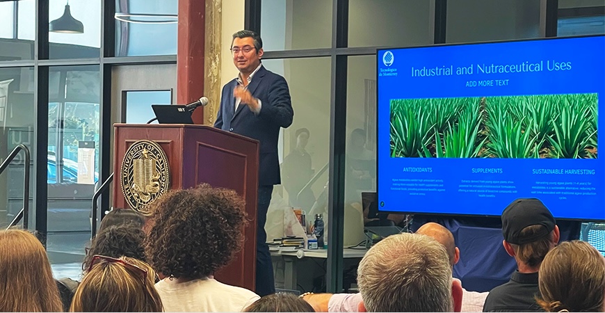 Depicted is César Armando Puente Garza of Tecnológico de Monterrey, speaking at a podium at UC Merced on Main.