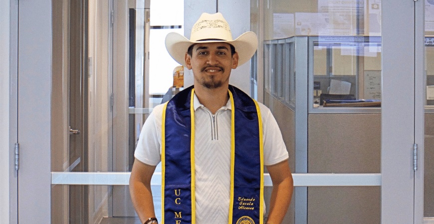 Depicted is UC Merced graduate Eduardo Savala Alvarez, in a cowboy hat and stole on campus.